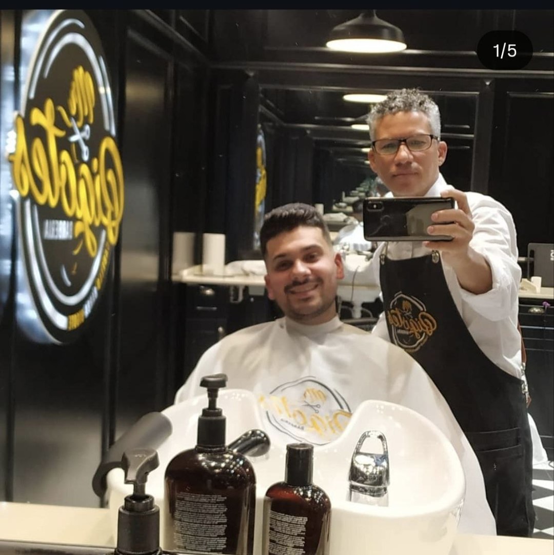 Elvyn con un cliente en su barbería